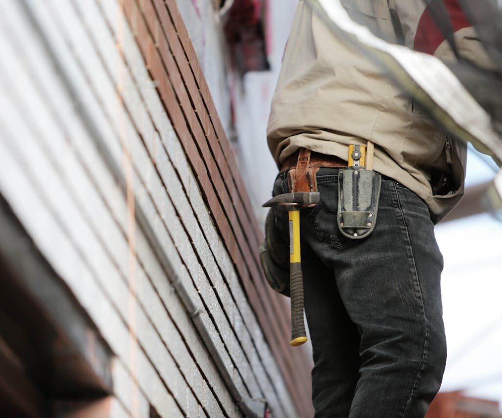 Close-up of a construction worker with hammer and tools, focused on the job.